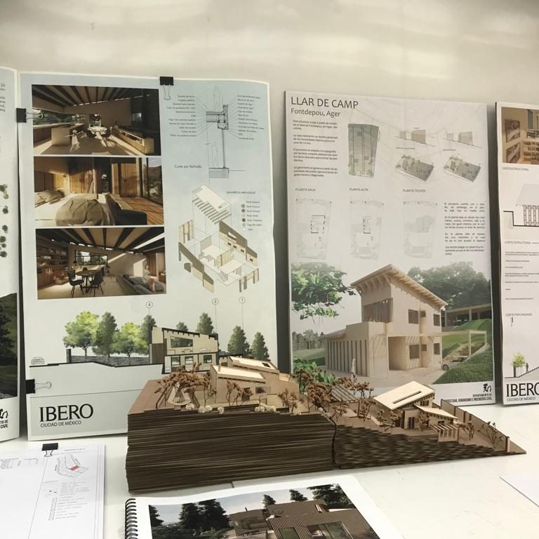 Modelo arquitectónico con planos y renders en un espacio de presentación.