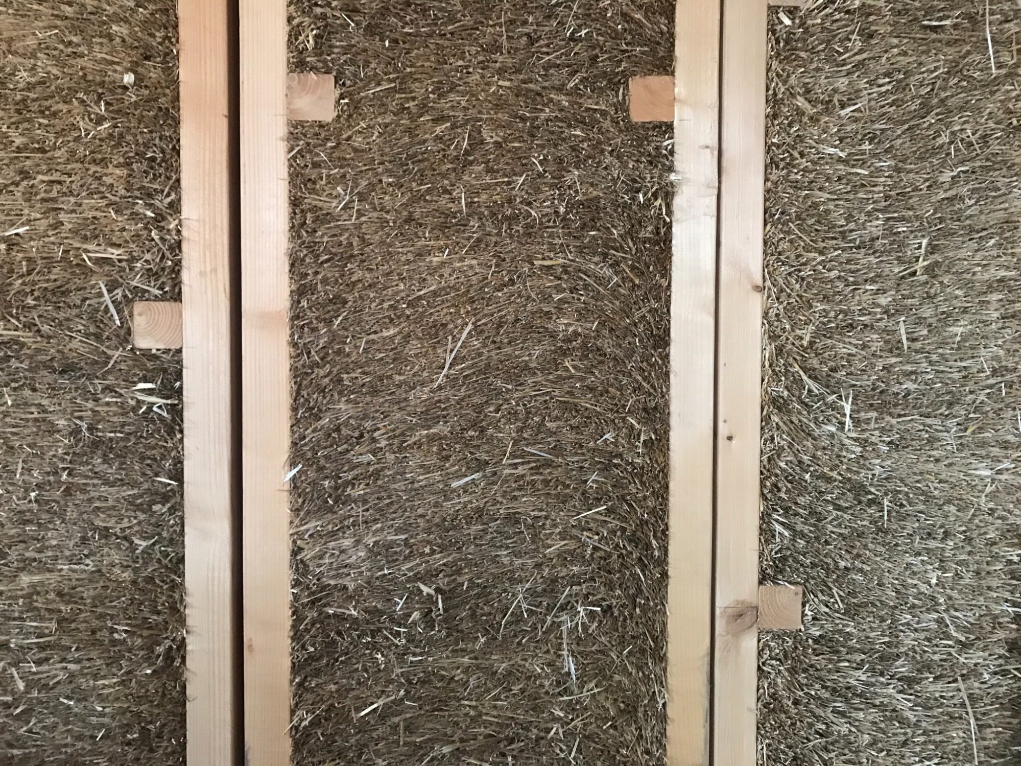 Pared con paneles de madera y relleno de paja entre ellos.