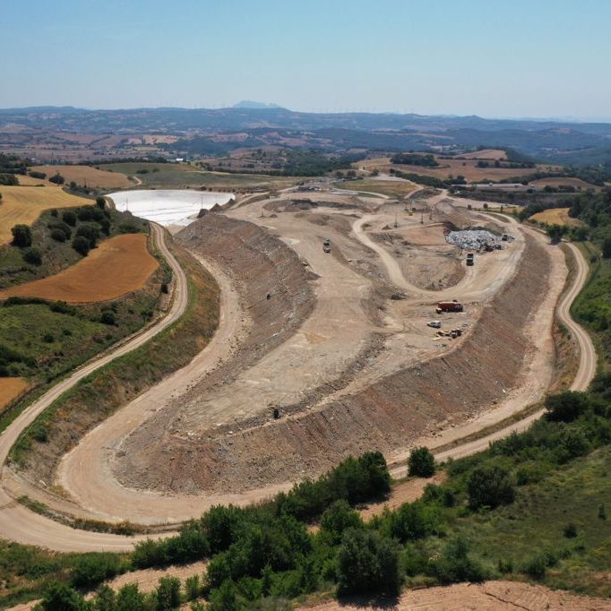 Vista panorámica de un terreno excavado, con áreas verdes y caminos de tierra.
