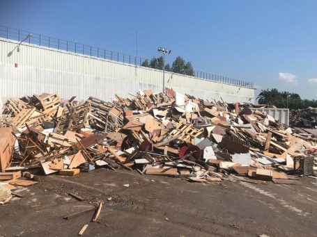 Montón de escombros y palets de madera apilados bajo un cielo despejado.